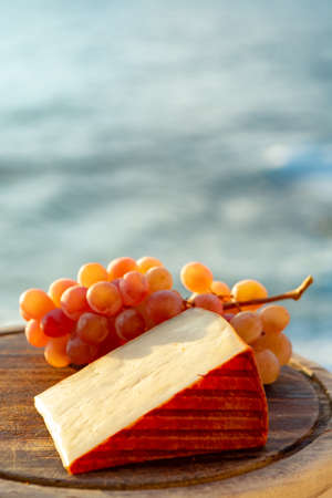 Spanish goat milk cheese with paprika coating and ripe pink table grapes close upの写真素材