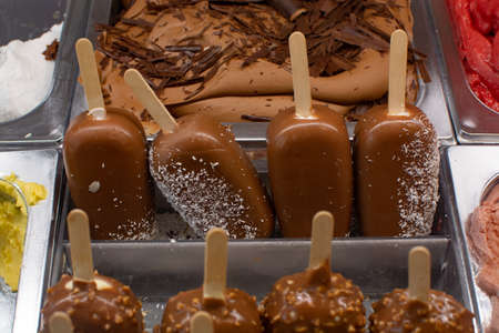 Variety of homemade chocolate, vanilla, almonds ice cream bars on sticks close up