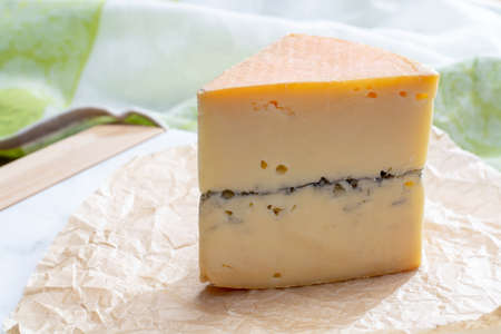 French semi-soft cow milk cheese morbier from Franche-Comte region with thin black layer and strong...