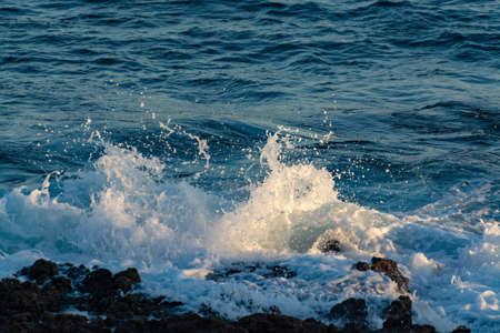 Background with dark blue ocean water waves close up on sunset