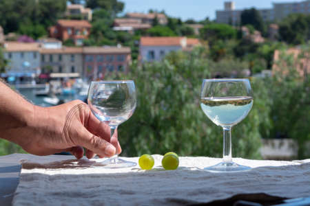 Waiter pouring white wine on outdoor cafe terrace in sunny summer day in Franceの写真素材