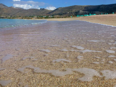 Surf waves on famous pink Falassarna beach with white and pink sand and exotic blue waters on Crete...