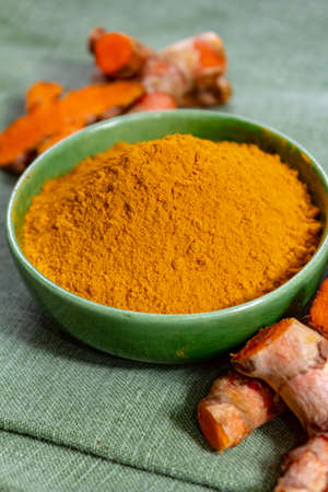 Fresh turmeric or curcuma root and dried powder, wildly used in Asia and India as spice, food ingredient and for medicinal purposes  close upの写真素材