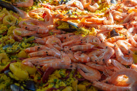 Street food in France, fresh prepared colorful paella with rice and sea food in big pan on street market, ready to eatの写真素材