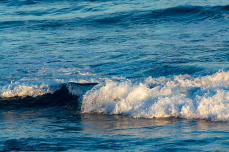 Background with dark blue ocean water waves close up on sunsetの写真素材