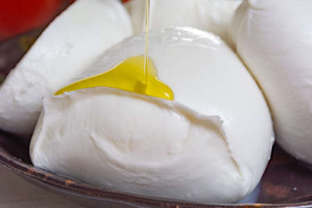 Balls and pieces of buffalo mozzarella, soft Italian scheese made from the milk of Italian...