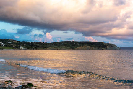 Dramatic sunset over sea water with gray clouds and sun lights, nature seascapeの写真素材