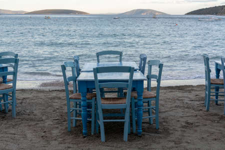 Traditional greek tavern with wooden tables on sandy beach near water waiting for tourists in Tolo, Peloponnese, Greece, vacation season is startingの写真素材