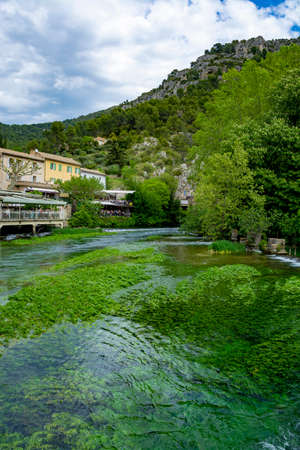 South of France, view on small touristic Provencal town of poet Petrarch Fontaine-de-vaucluse with emerald green waters of Sorgue riverの写真素材