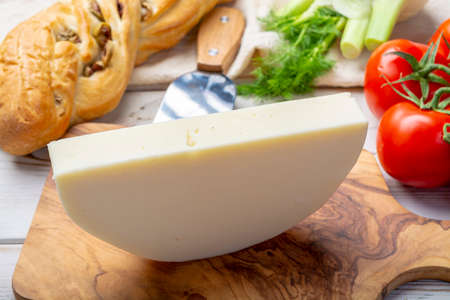 Italian cheese, Provolone dolce cow cheese from Cremona served with olive bread and tomatoes close upの写真素材