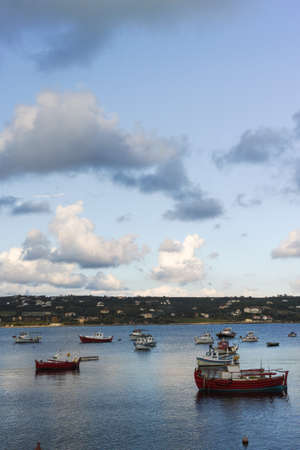 Seascape with sea harbor with clear blue water and traditional colorful greek fisher boats on sunset
