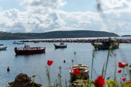 Landscape with colorful spring wild flowers, quiet sea harbor and traditional greek fisher boats