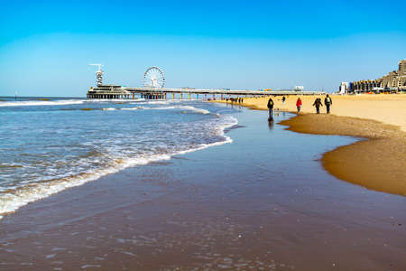 People walking in sunny day on North sea beach in Netherlands near Schegeningen, tourist and vacation destination in Europeの写真素材