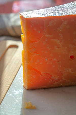 Cheese collection, one piece of three years old dark yellow hard Dutch cheese in sun lights