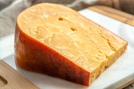 Cheese collection, one piece of three years old dark yellow hard Dutch cheese in sun lightsの写真素材