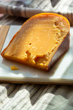 Cheese collection, one piece of three years old dark yellow hard Dutch cheese in sun lightsの写真素材