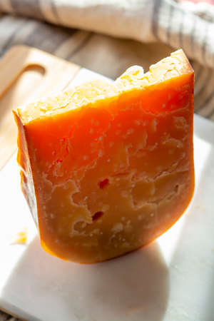 Cheese collection, one piece of three years old dark yellow hard Dutch cheese in sun lights