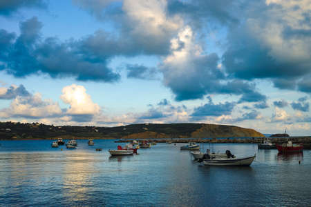 Seascape with sea harbor with clear blue water and traditional colorful greek fisher boats on sunsetの写真素材
