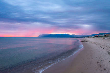 Scenic pink-red sunrise over coastline with sandy beach and clear sea water in Alcamo Marina, small town in Sicily, Italy, summer vacation destinationの写真素材