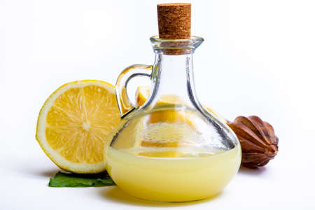 Fresh lemon juice made from ripe yellow Sicilian lemons used for cooking in glass bottle on olive...