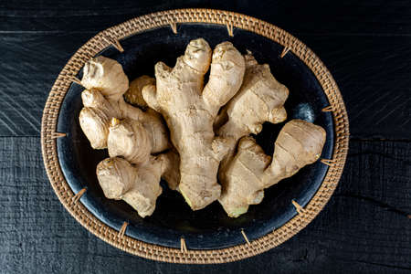 Fresh ginger roots close up on black wooden background, asian food concept