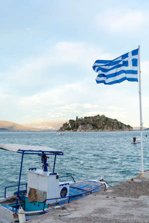 National symbol of Greece, blue-white greek flag on flagpole, sea water and blue sky, copy space