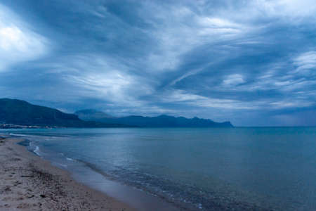 Scenic gray-blue clouds during sunrise over coastline with sandy beach in Alcamo Marina, small town in Sicily, Italy, summer vacation destinationの写真素材