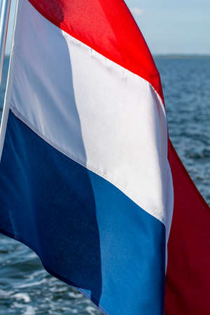 Dutch red white blue flag on sea water background close upの写真素材