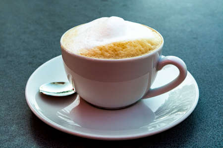 Italian coffee capuccino with foaming milk served on gray tableの写真素材