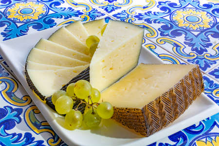 Spanish sheep cheese served with white grapes on andalusian style table