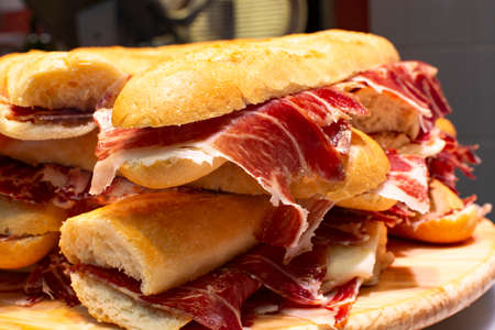 Spanish tapas street food, bocadillo fresh bread with jamon iberico ready to eat