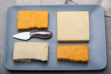 Cheese collection, matured and orange original British cheddar cheese in blocks served on grey plate...