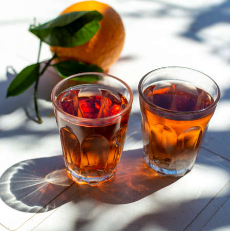 Young rose wine served outside in garden on white table with fresh orange in sun lights close up