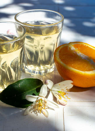 White wine served outside in garden on white table with fresh orange in sun lights close upの写真素材