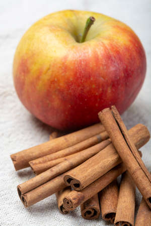 Winter pastry food ingredient, dried aromatic cinnamon sticks and apple on tin plate close upの写真素材