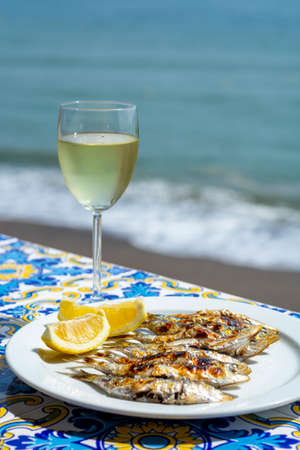 Sardines espeto, Malaga style fish on stick barbecue prepared on olive tree firewoods on beach served with white wineの写真素材