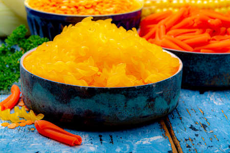 Yellow and orange gluten free diet pasta made from orange lentils and  corn cereal on blue wooden...