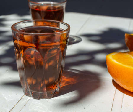 Young rose wine served outside in garden on white table with fresh orange in sun lights close upの写真素材