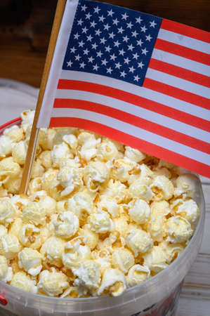 Plastic bucket with tasty sweet popcorn ready to eat and flag of USAの写真素材