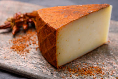 Cheese collection, piece of Spanish manchego cheese made from cow milk with red paprika close upの写真素材