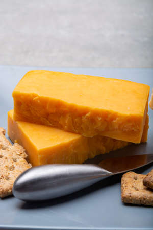 Cheese collection, matured and orange original British cheddar cheese in blocks served on grey plate close upの写真素材