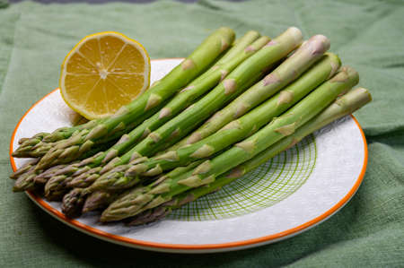 Bunch of fresh green raw organic asparagus with lemon ready to cook close upの写真素材