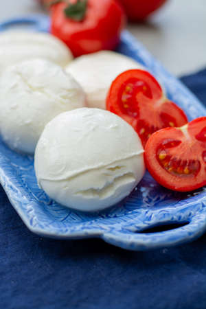 Cheese collection, fresh Italian soft mozzarella cheese in balls served with red ripe tomatoes close upの写真素材
