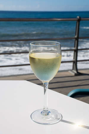 Summer holiday on sea, drinking white wine on outdoor terrace with ocean view in sunny dayの写真素材