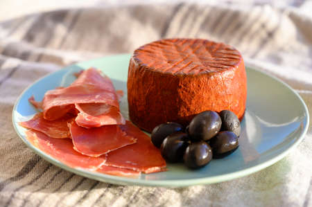 Tastes of Spain, jamon iberian, black olives and manchego cheese with red paprika close up in sun lightsの写真素材