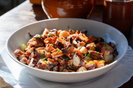 Tastes of Spain, fresh homemade Galician octopus salad with red paprika and parsley served outside on tableの写真素材
