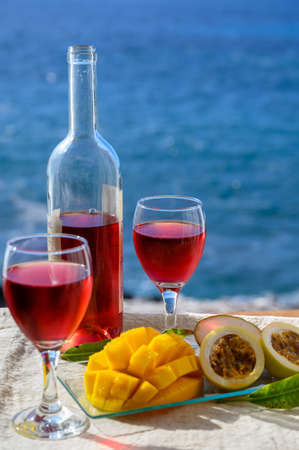 Two glasses of cold rose wine served outdoor with exotic fruits on tropical island La Palma, Canary islands, Spain with beautiful blue ocean viewの写真素材