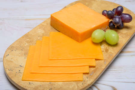 Cheese collection, block and slices of yellow english cheddar cheese close upの写真素材