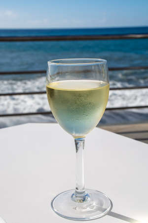 Summer holiday on sea, drinking white wine on outdoor terrace with ocean view in sunny dayの写真素材