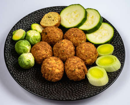 Cooking of healthy vegetarian food, tasty check pea falafels and frehs green vegetables close up